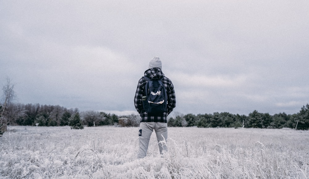 man in black jacket standing on grass field