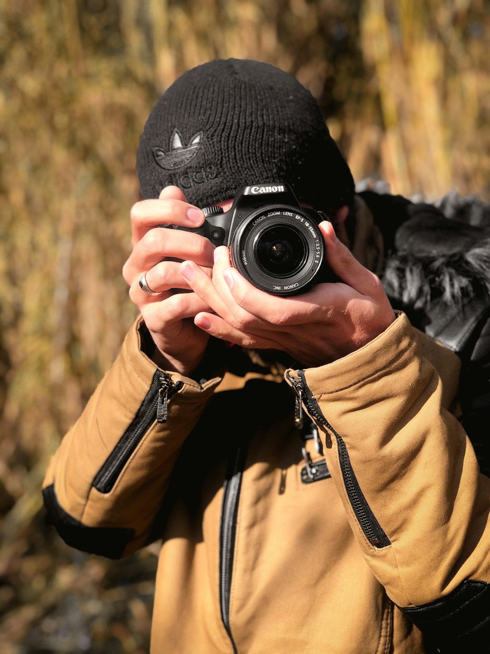 person in black knit cap holding black camera