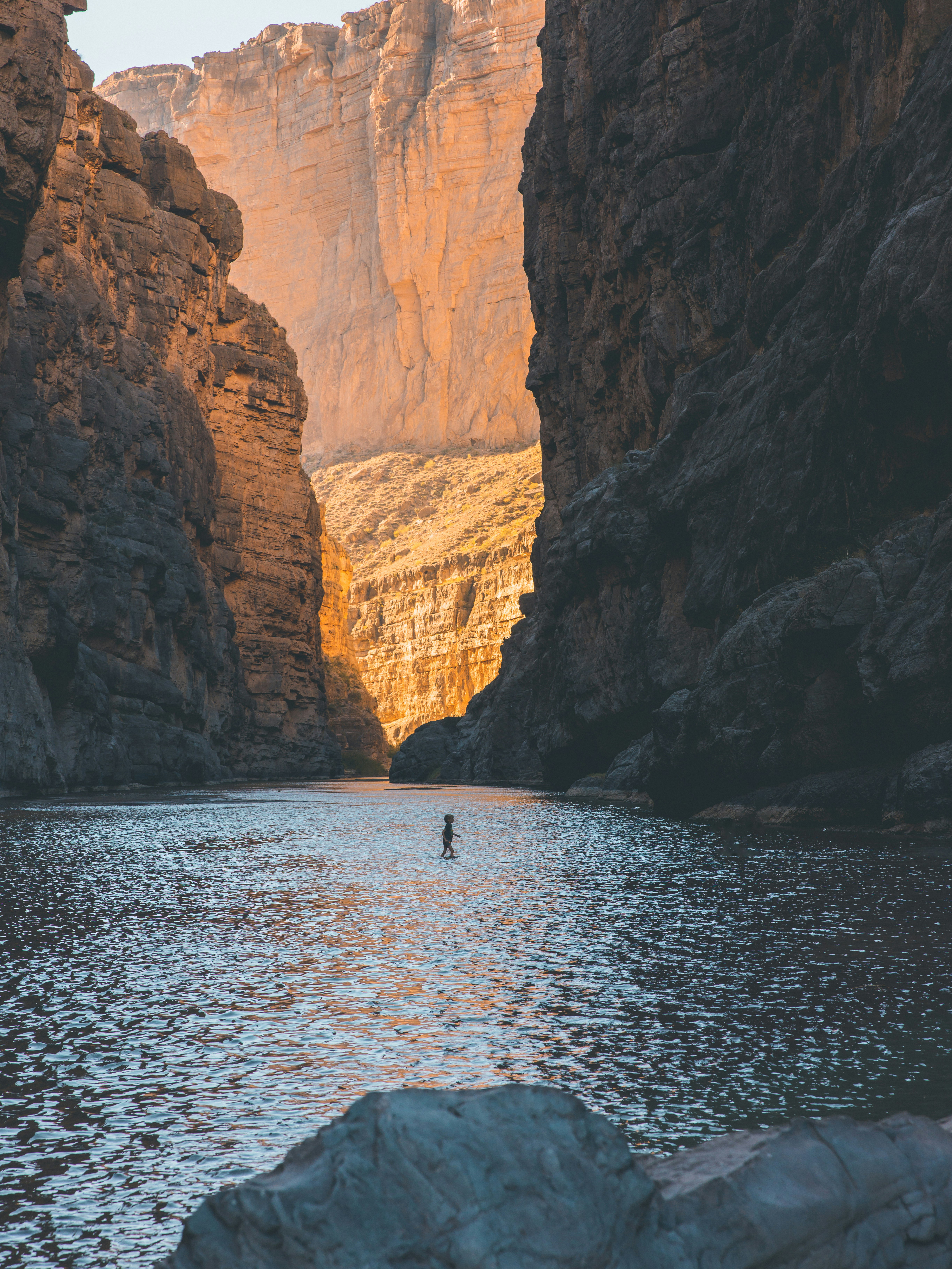 people riding boat on sea near brown rocky mountain during daytime