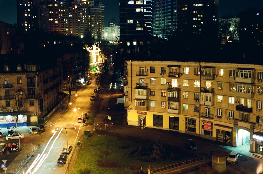 cars parked on side of the road in between high rise buildings during night time