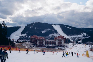 people on snow covered ground near mountain under cloudy sky during daytime