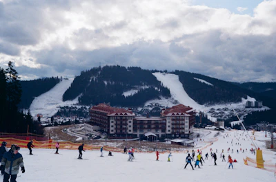people on snow covered ground near mountain under cloudy sky during daytime