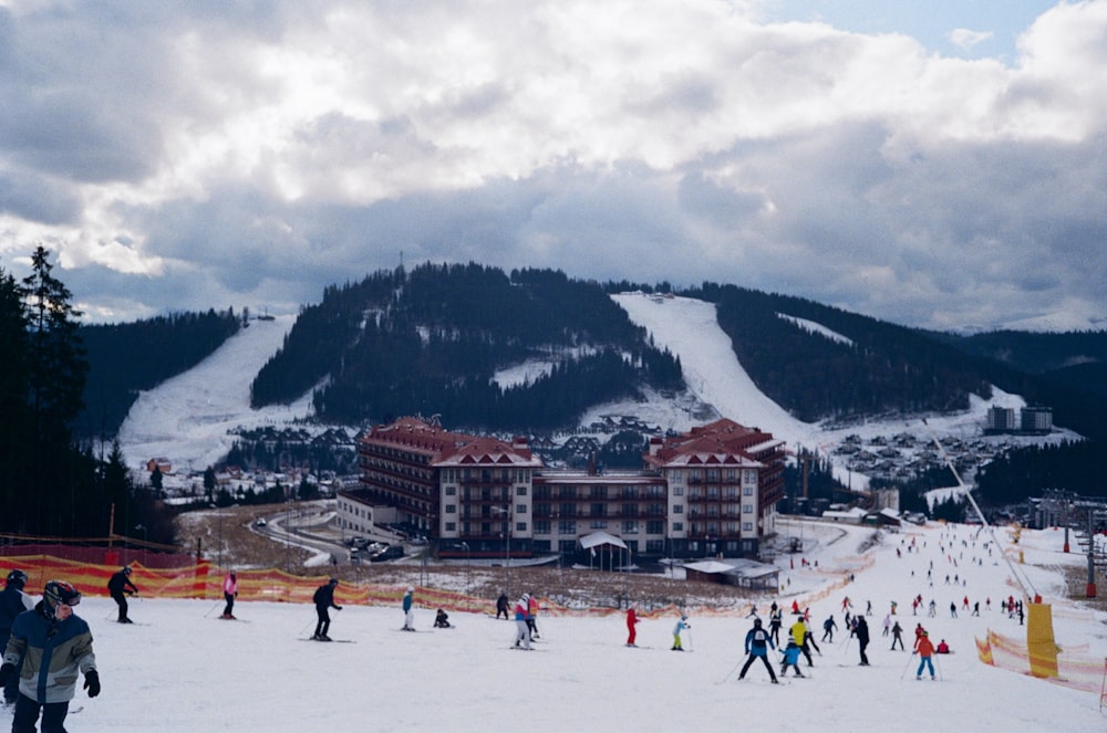 people on snow covered ground near mountain under cloudy sky during daytime