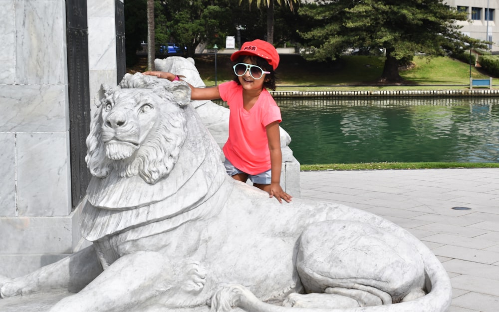 woman in red polo shirt and black pants sitting on white horse statue