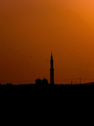 A peaceful mosque silhouette at sunset with subtle geometric patterns in the sky.