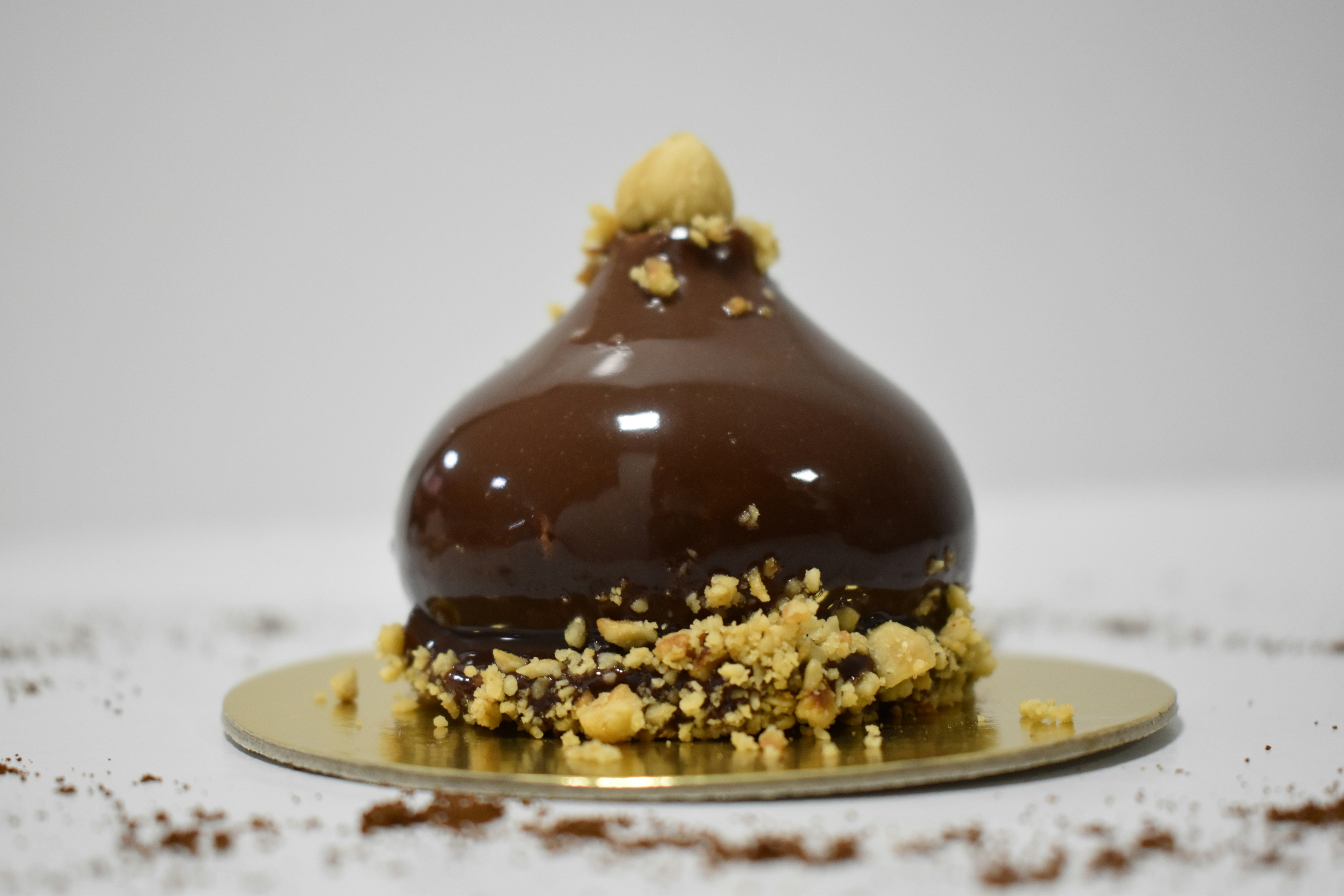 Chocolate dome cake with cherry on top served on a golden plate
