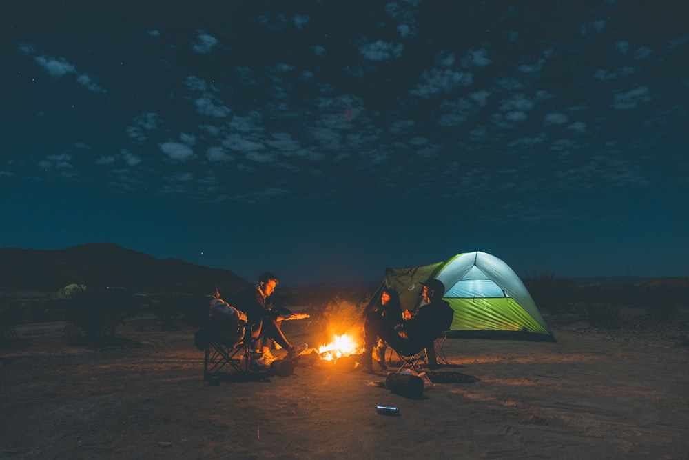 people sitting on camping chairs near bonfire during night time