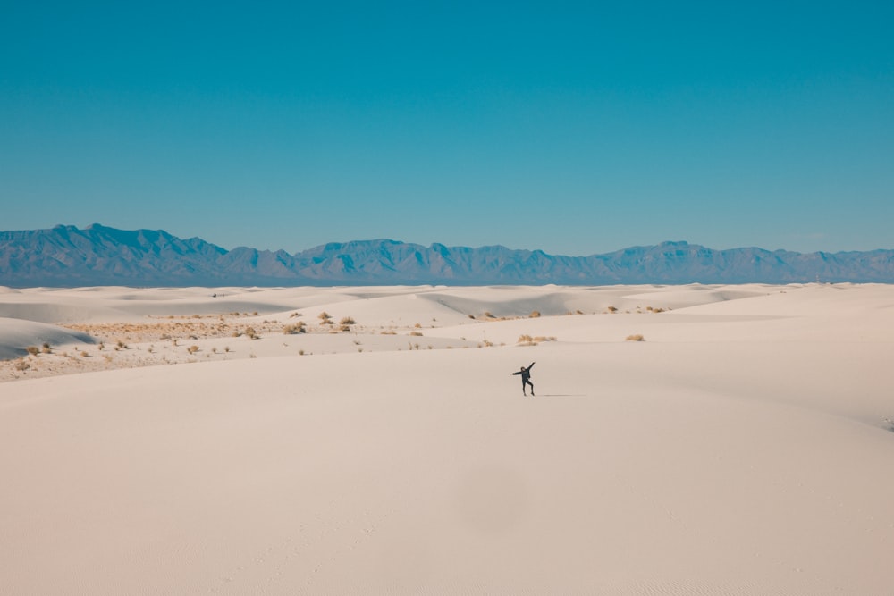 person walking on white sand during daytime