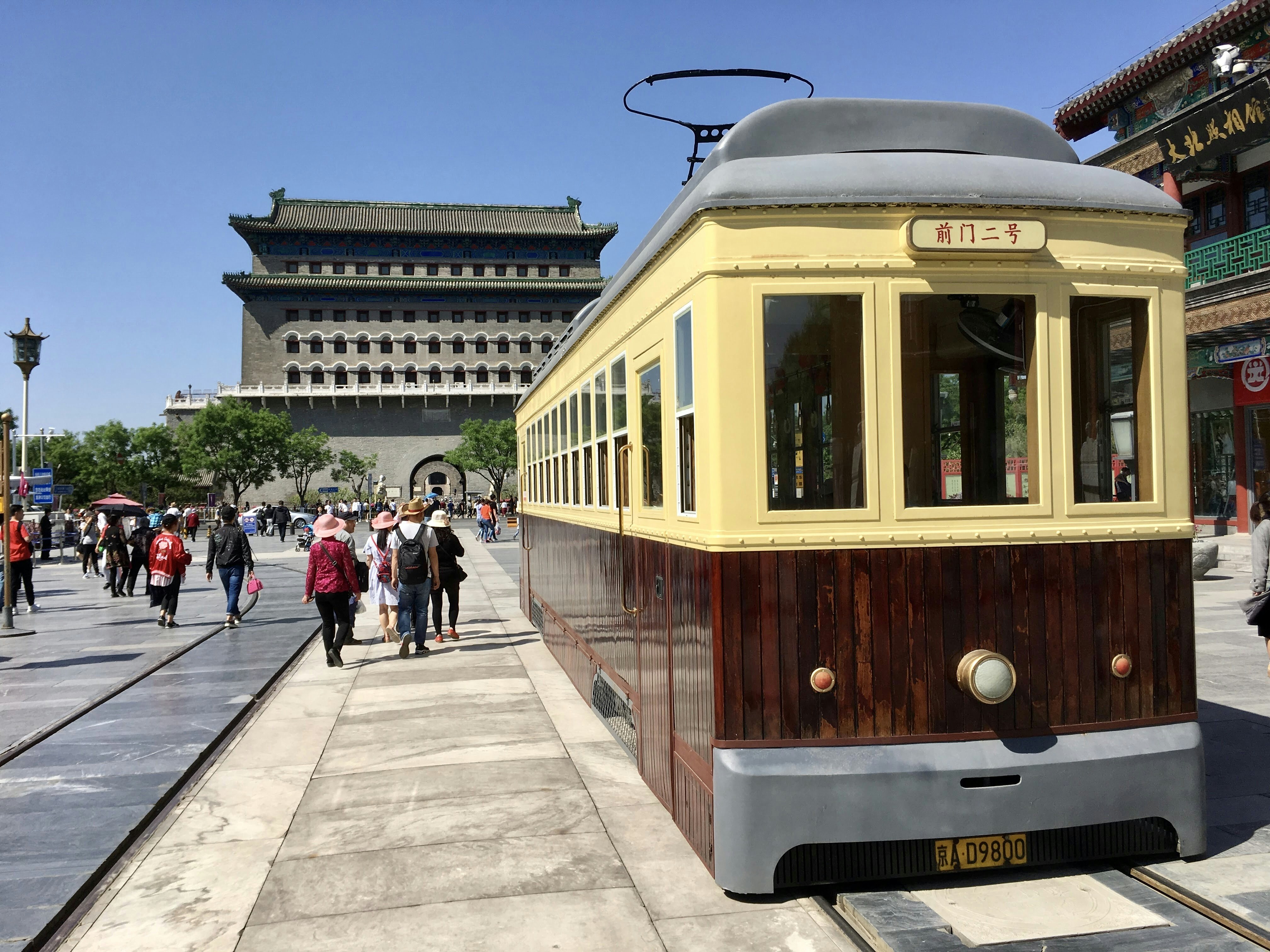 people walking on sidewalk near white and brown train during daytime