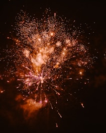 Close-up of a fiery explosion of colorful fireworks lighting up a night sky.
