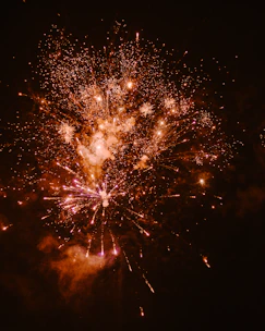Close-up of a fiery explosion of colorful fireworks lighting up a night sky.