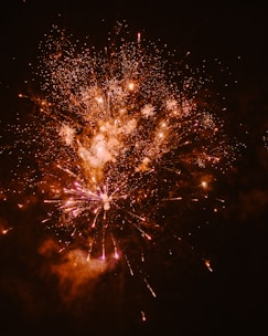 Close-up of a fiery explosion of colorful fireworks lighting up a night sky.