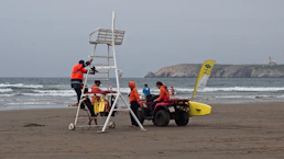 2 men in red and yellow life vest riding red and yellow atv on beach during