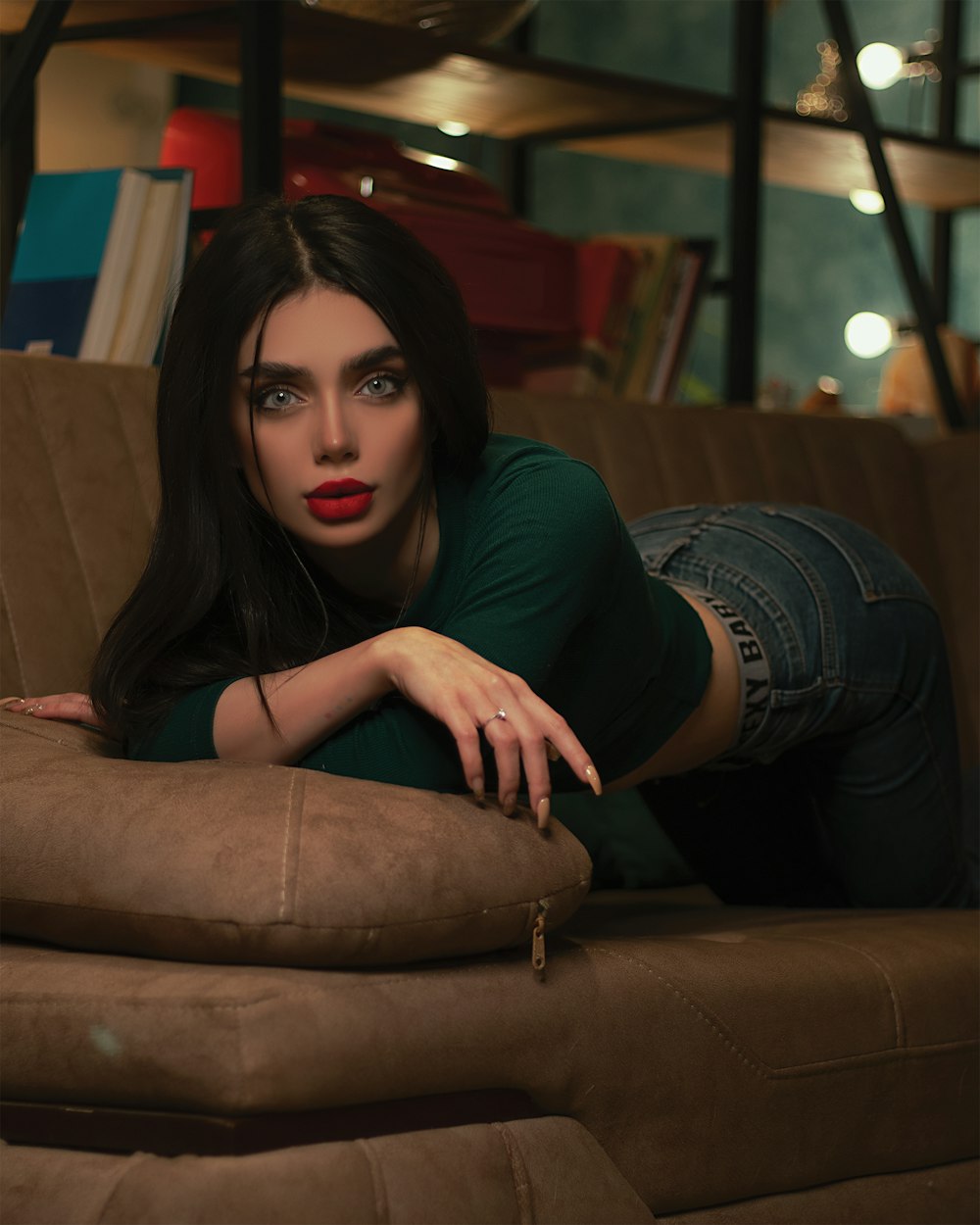 woman in black shirt and blue denim jeans sitting on brown leather couch