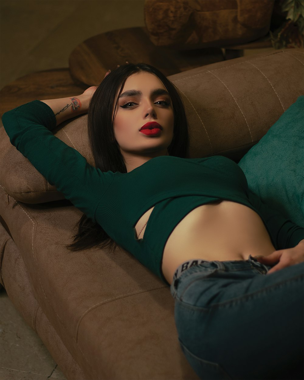 woman in black long sleeve shirt and blue denim jeans lying on green sofa