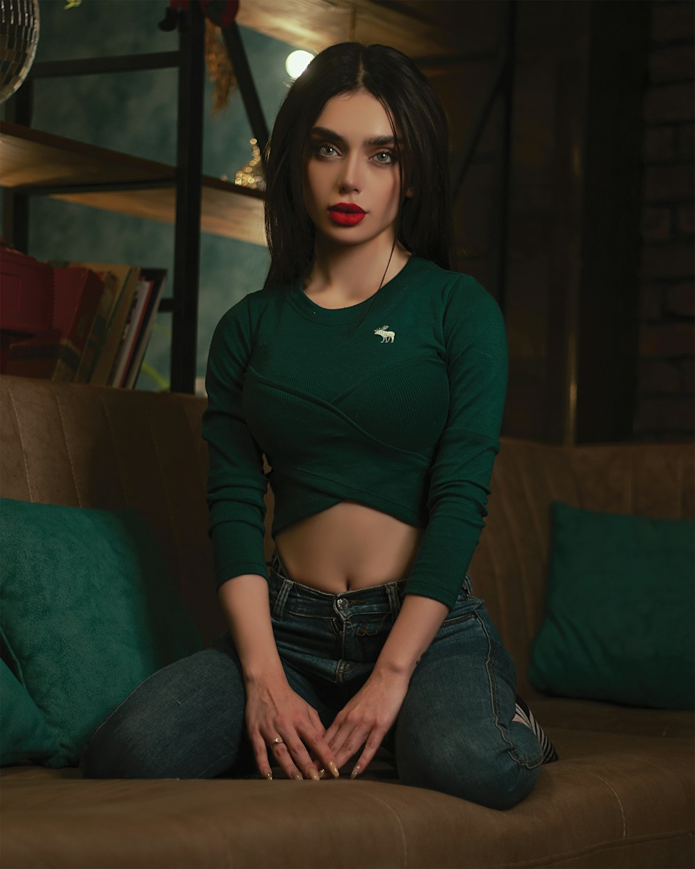 woman in maroon long sleeve shirt and blue denim jeans sitting on green couch