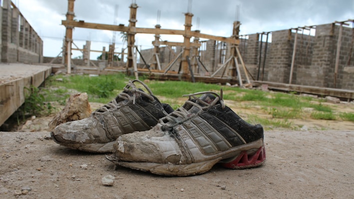 Close-up of rugged work boots covered in dust on a construction site.