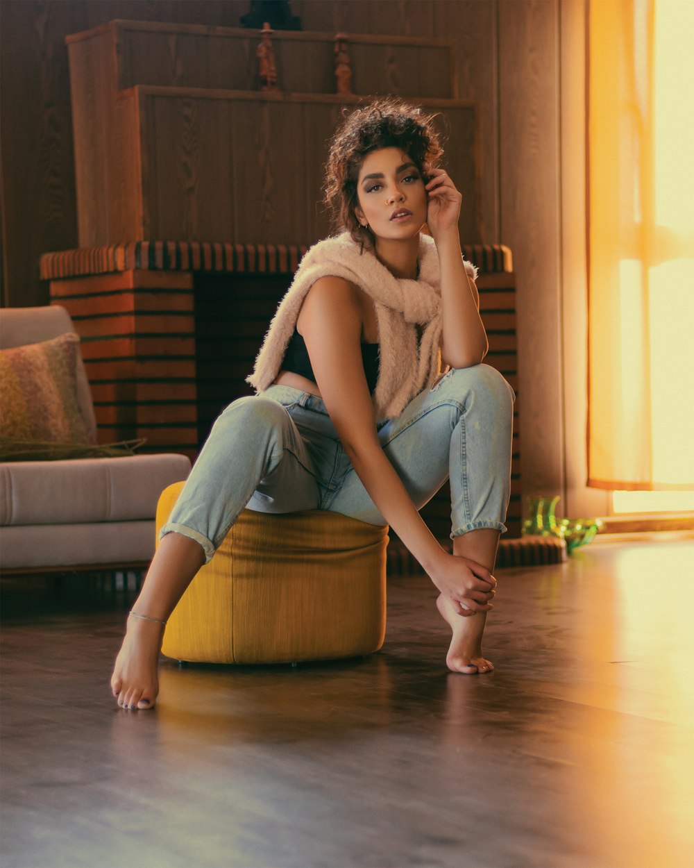 woman in white tank top and blue denim jeans sitting on brown wooden floor