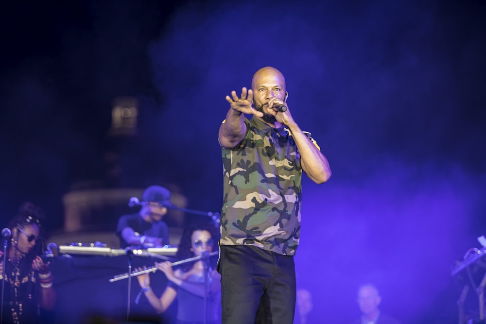 man in green and brown camouflage shirt singing on stage