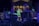 A concert scene features a performer in a green shirt and dark shorts energetically singing into a microphone. The stage is illuminated with colorful lights, and musical equipment including drums and a DJ setup are visible. In the background, a large building can be seen.