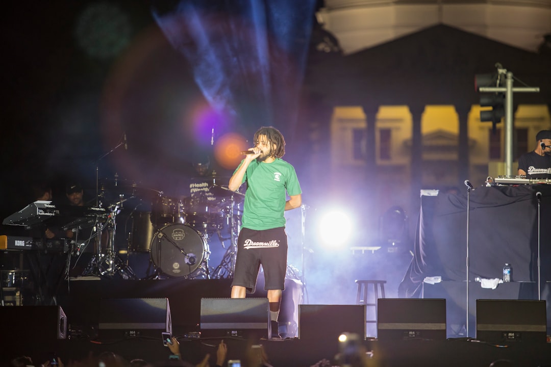 man in green crew neck t-shirt standing on stage