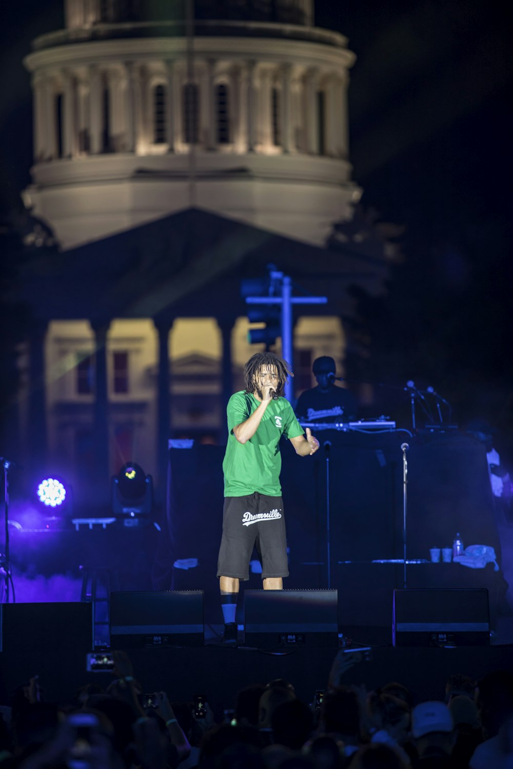 man in white long sleeve shirt singing on stage