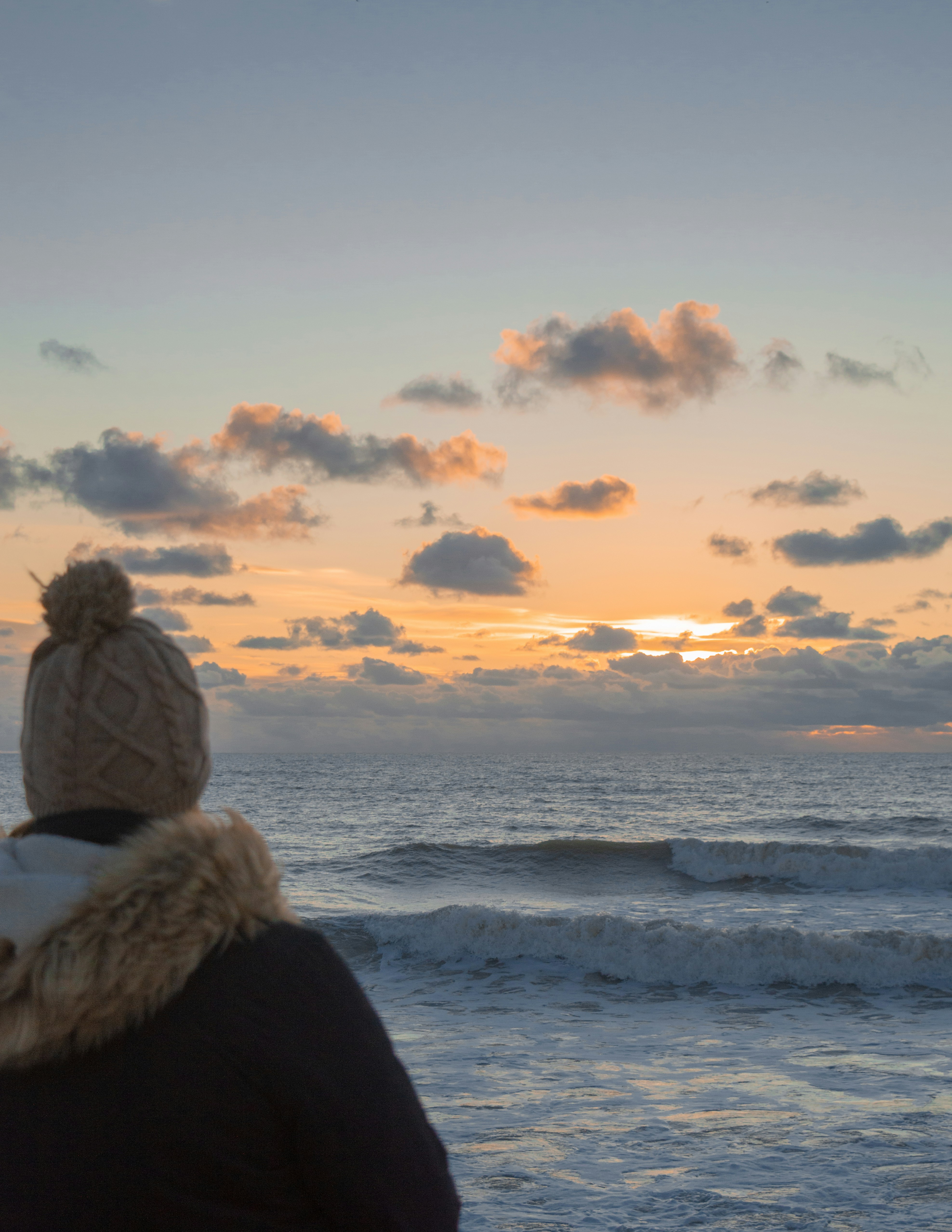 woman in white fur coat standing on seashore during daytime