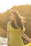 Smiling woman wearing a bright summer dress outdoors with soft sunlight.