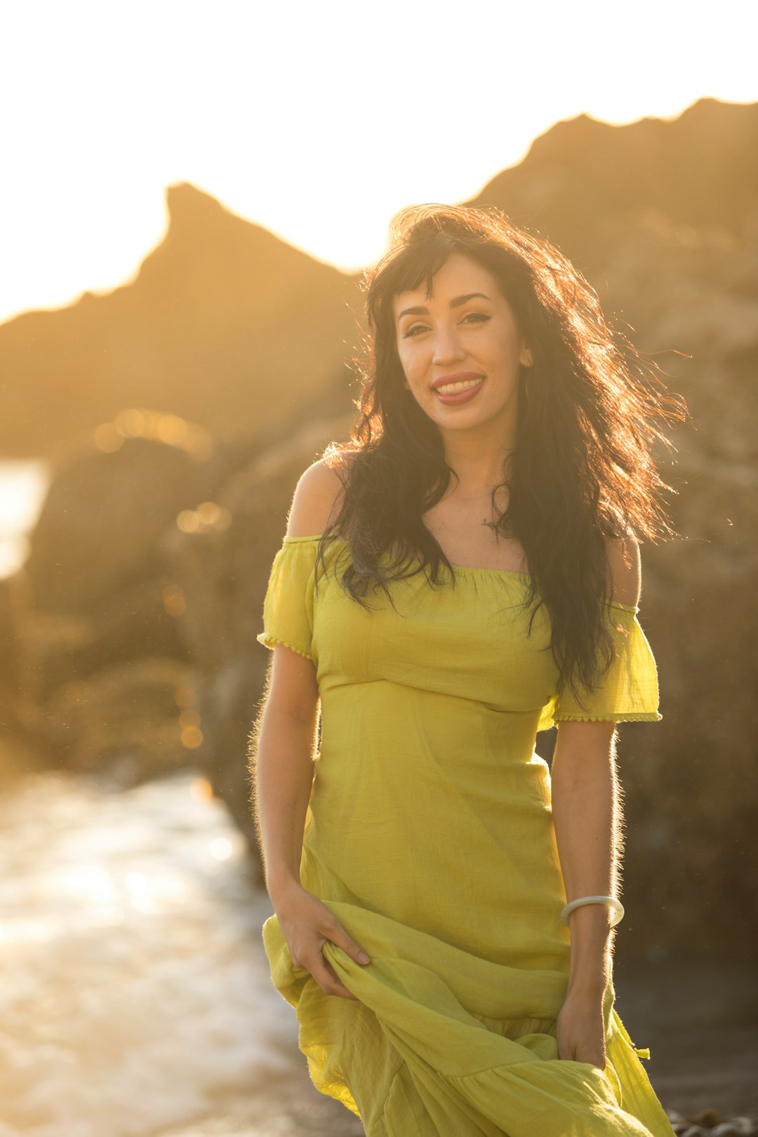 woman in yellow shirt standing near brown rock formation during daytime