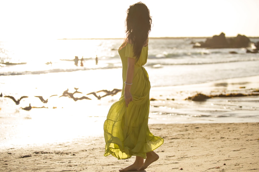 woman in yellow dress walking on beach during daytime