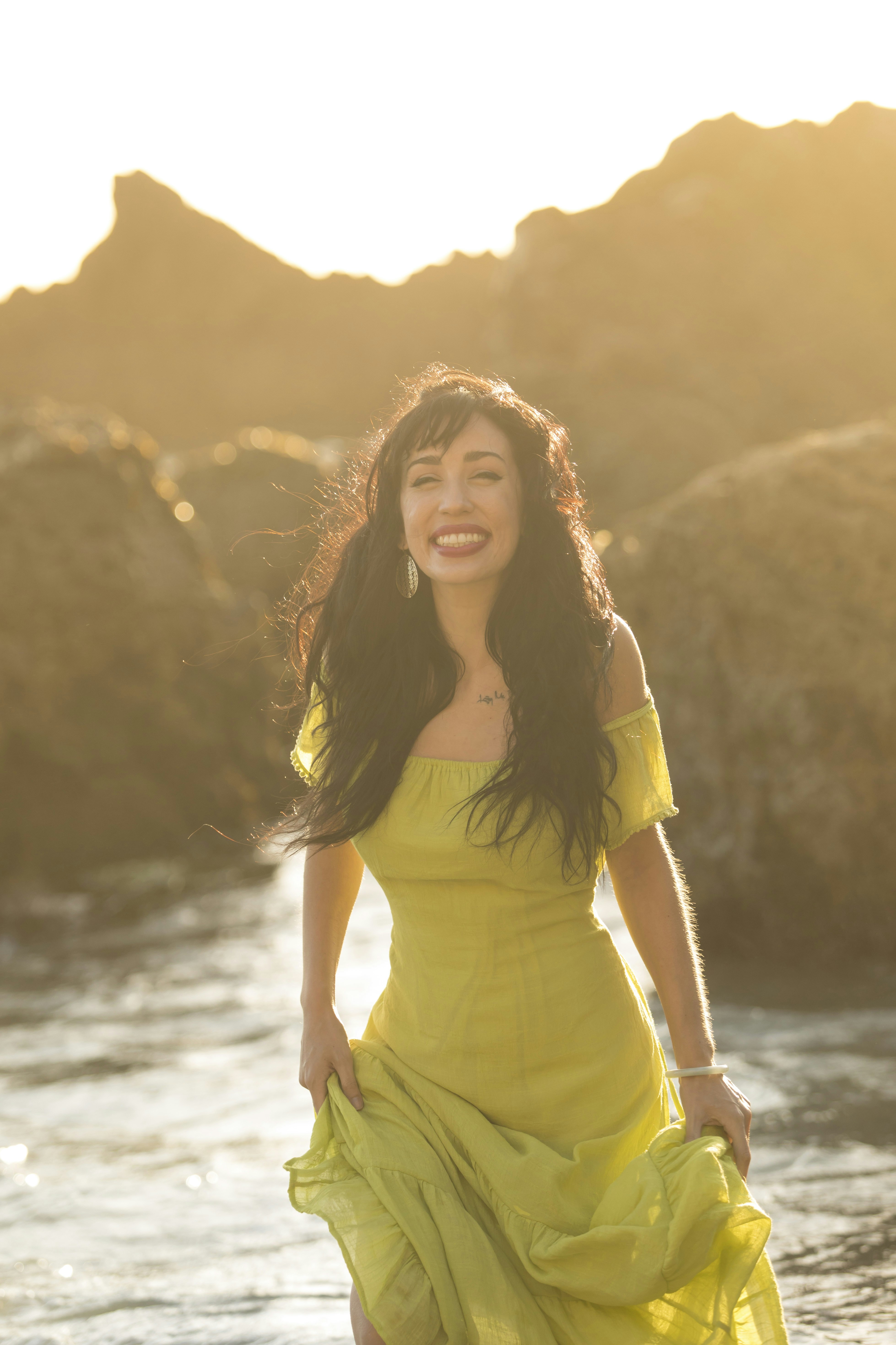 woman in yellow shirt standing near body of water during daytime