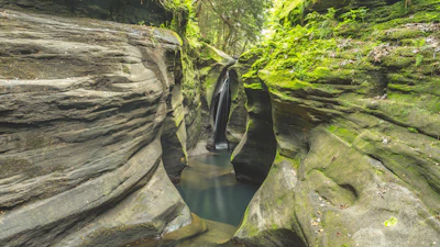 Beautiful hidden waterfall cascading over smooth rocks beside a narrow gorge in Ubud’s jungle