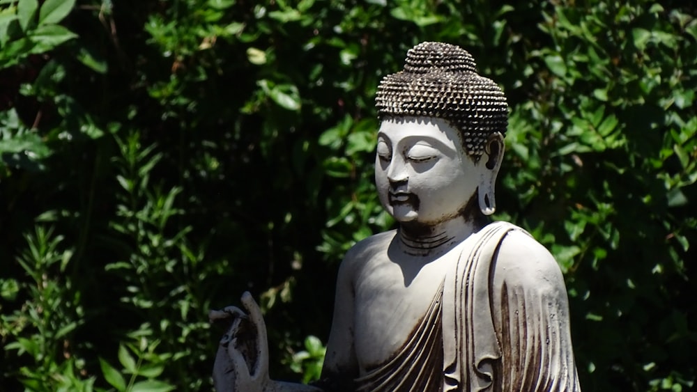 white concrete statue near green trees during daytime