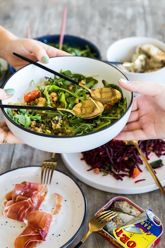 person holding white ceramic bowl with vegetable dish