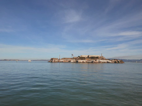 Historic black-and-white photo of Alcatraz prison's cell blocks under a foggy San Francisco sky.