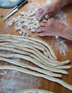 Close-up of little hands carefully rolling dough on a floured table.