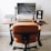 A modern workspace setup featuring a wooden desk with a large monitor displaying a leaf pattern, a laptop elevated on a stand, a digital clock showing the time as 11:08, a wireless keyboard and mouse, and a smartphone on a black mouse pad. An ergonomic brown leather chair is positioned in front of the desk, and the floor is carpeted.