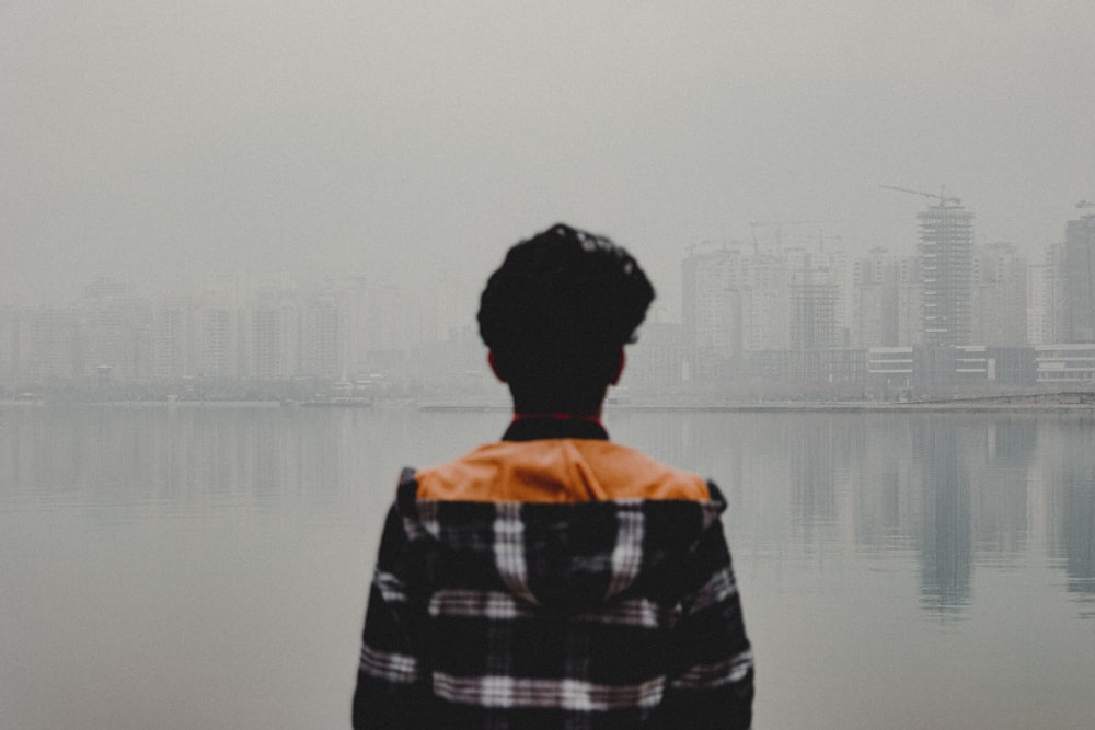 woman in black and white plaid dress shirt standing near body of water during daytime