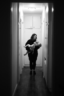 woman in black long sleeve shirt carrying baby in grayscale photography