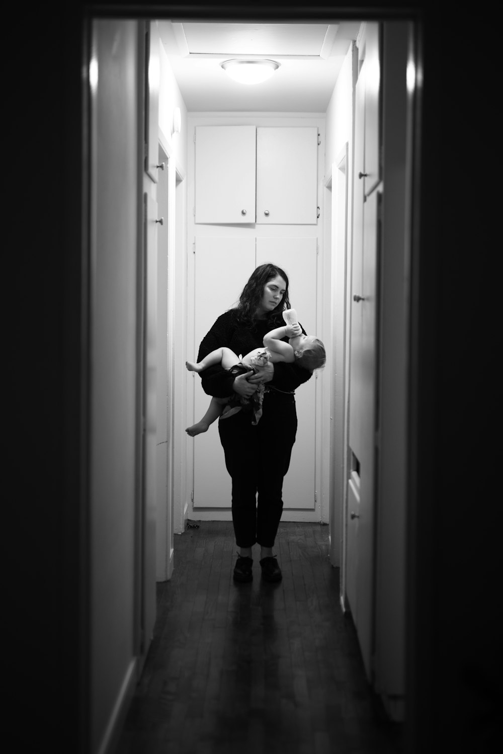 검은 긴 소매 셔츠를 입은 여자가 회색조 사진에서 아기를 안고 있다