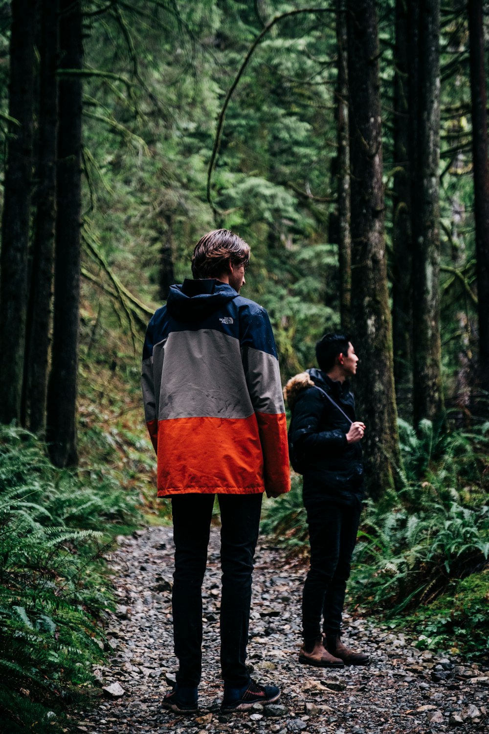 man in blue and red jacket and black pants carrying black and brown backpack