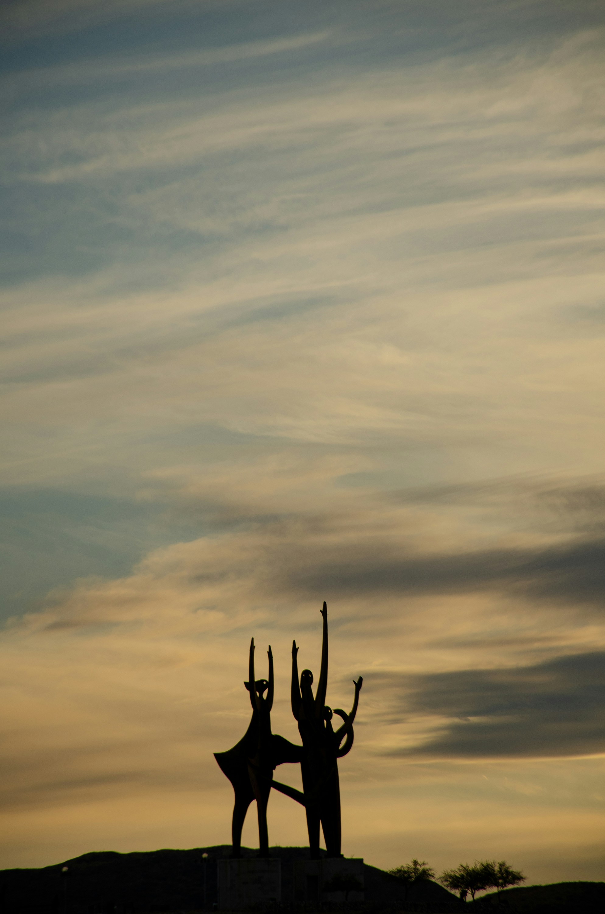 Silueta de 2 personas saltando en el aire bajo el cielo nublado durante el día