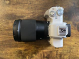 A sleek mirrorless camera with a large lens resting on a wooden table.