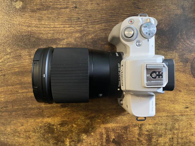 A sleek mirrorless camera with a large lens resting on a wooden table.