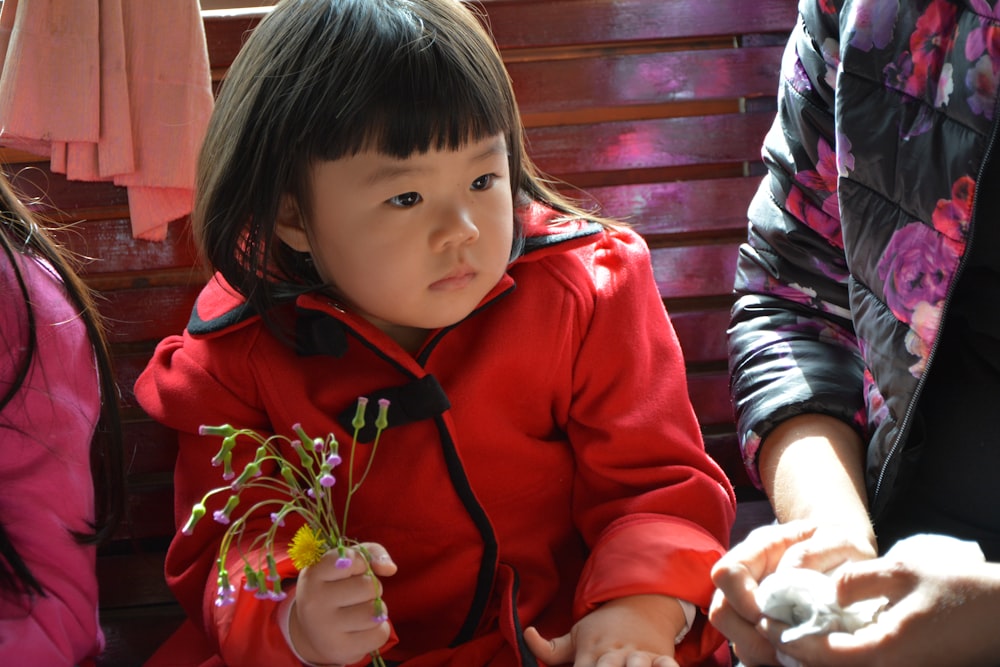 girl in red zip up jacket holding red rose