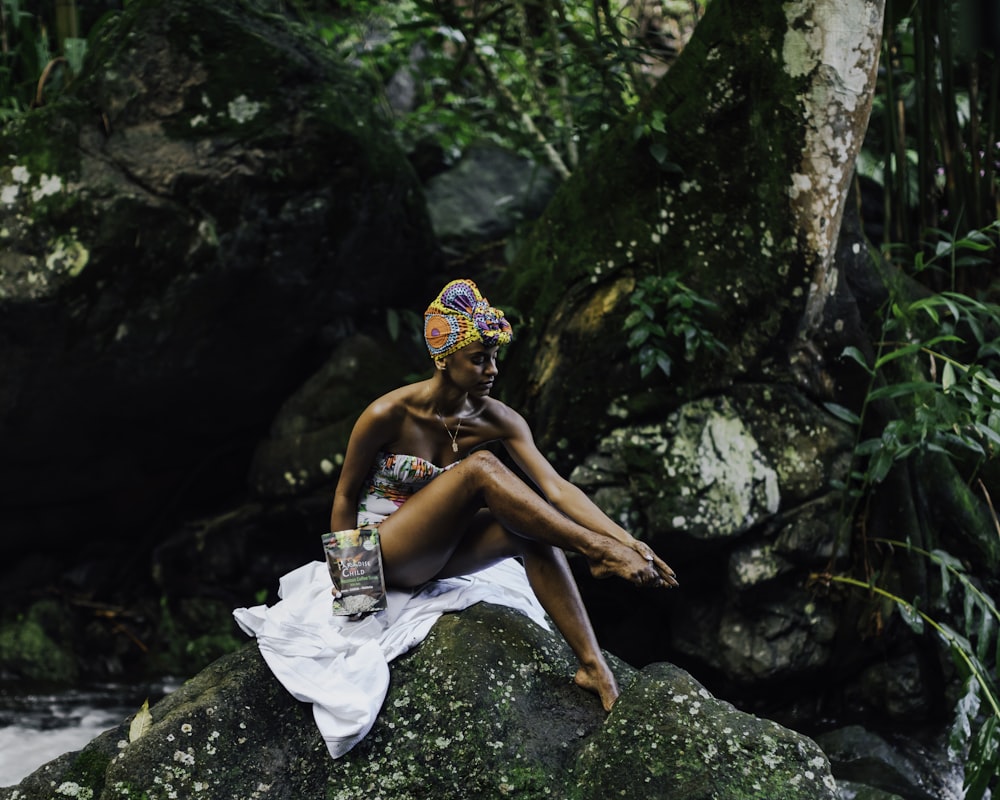 woman in white skirt sitting on rock