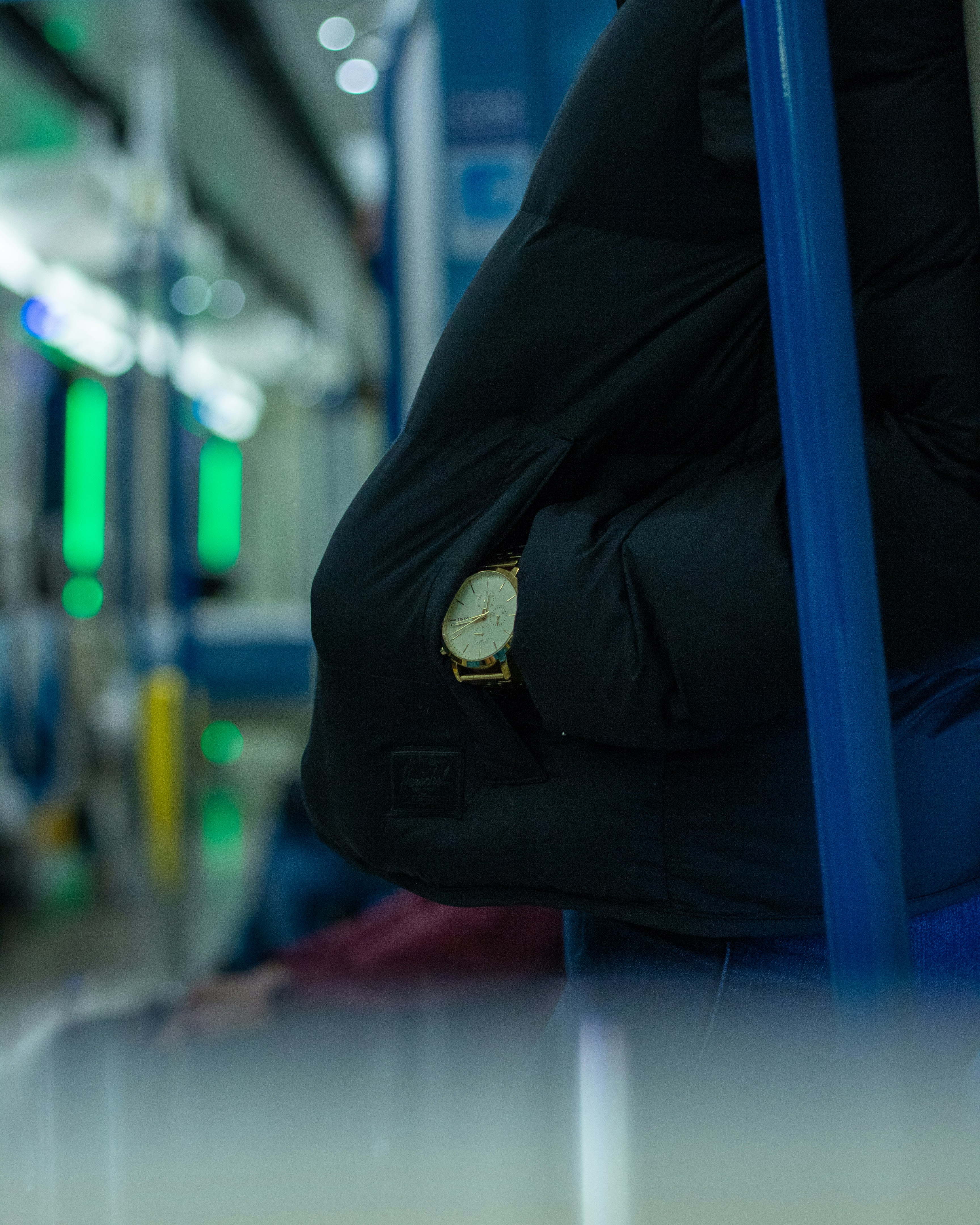 person in black jacket wearing gold round analog watch