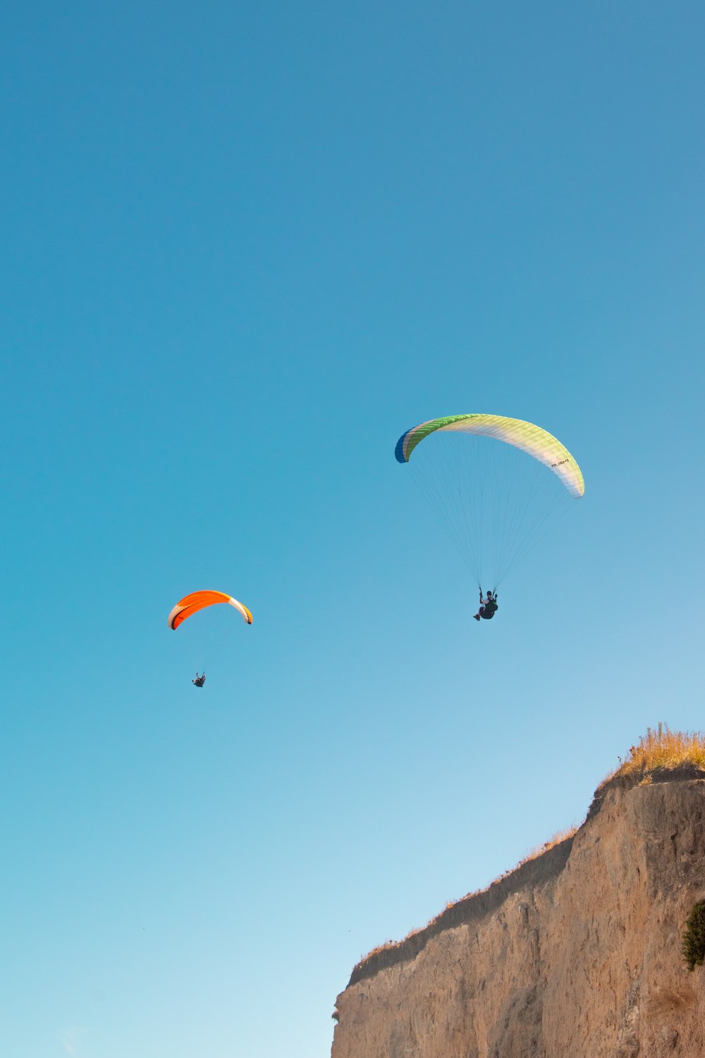 people riding parachute over brown mountain during daytime