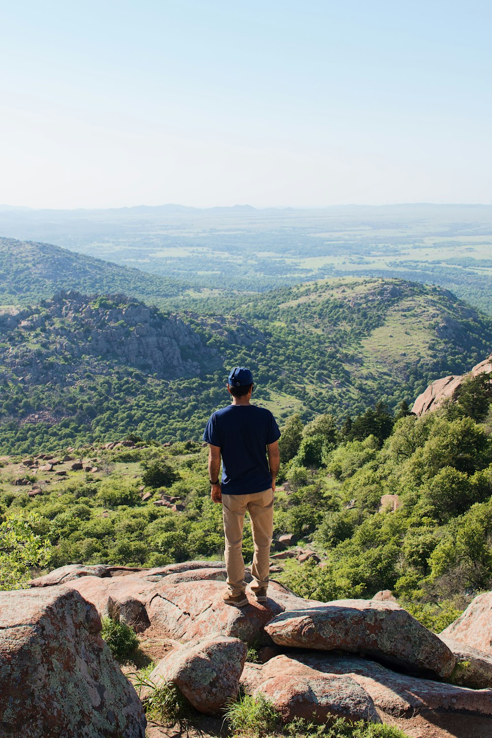 man in black shirt and brown shorts standing on cliff during daytime