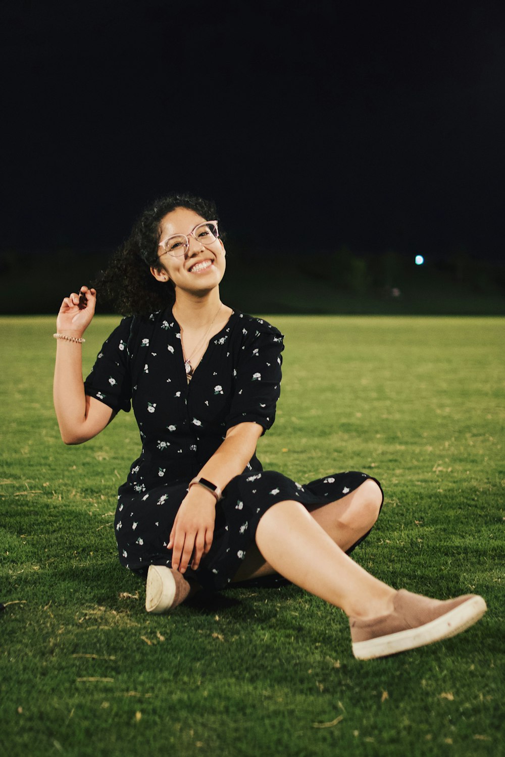 woman in black and white polka dot dress sitting on green grass field